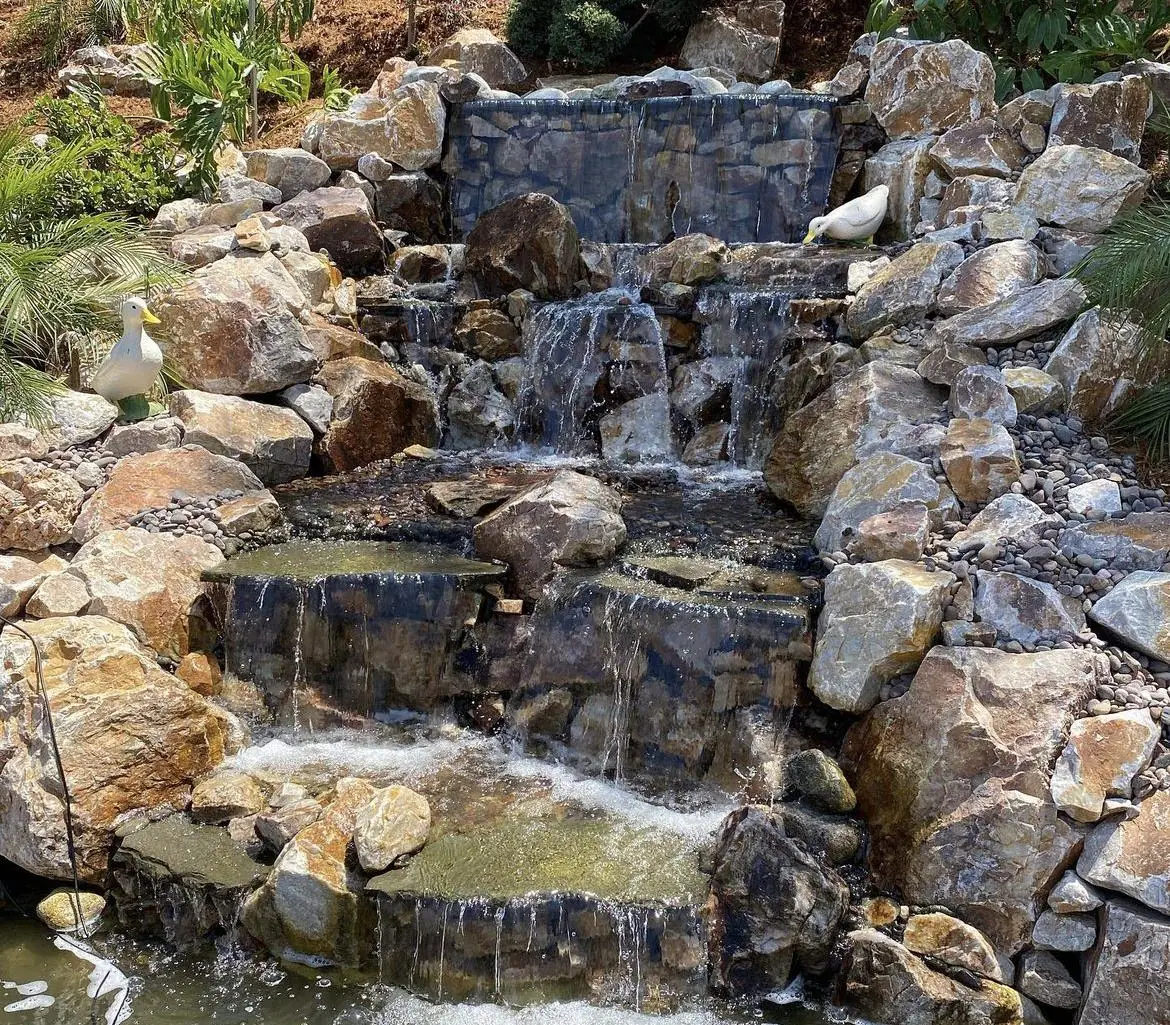 8-foot tall stone waterfall feeding a 55-foot stream built by The Pond Pros in Claremont, CA